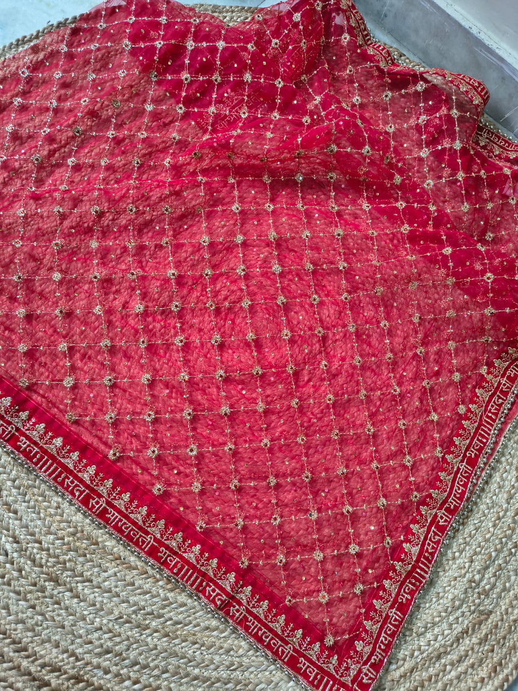 Full red net bridal dupatta laid flat on jute background showing complete gold zardozi diamond jaal embroidery and Sanskrit blessing border on all sides